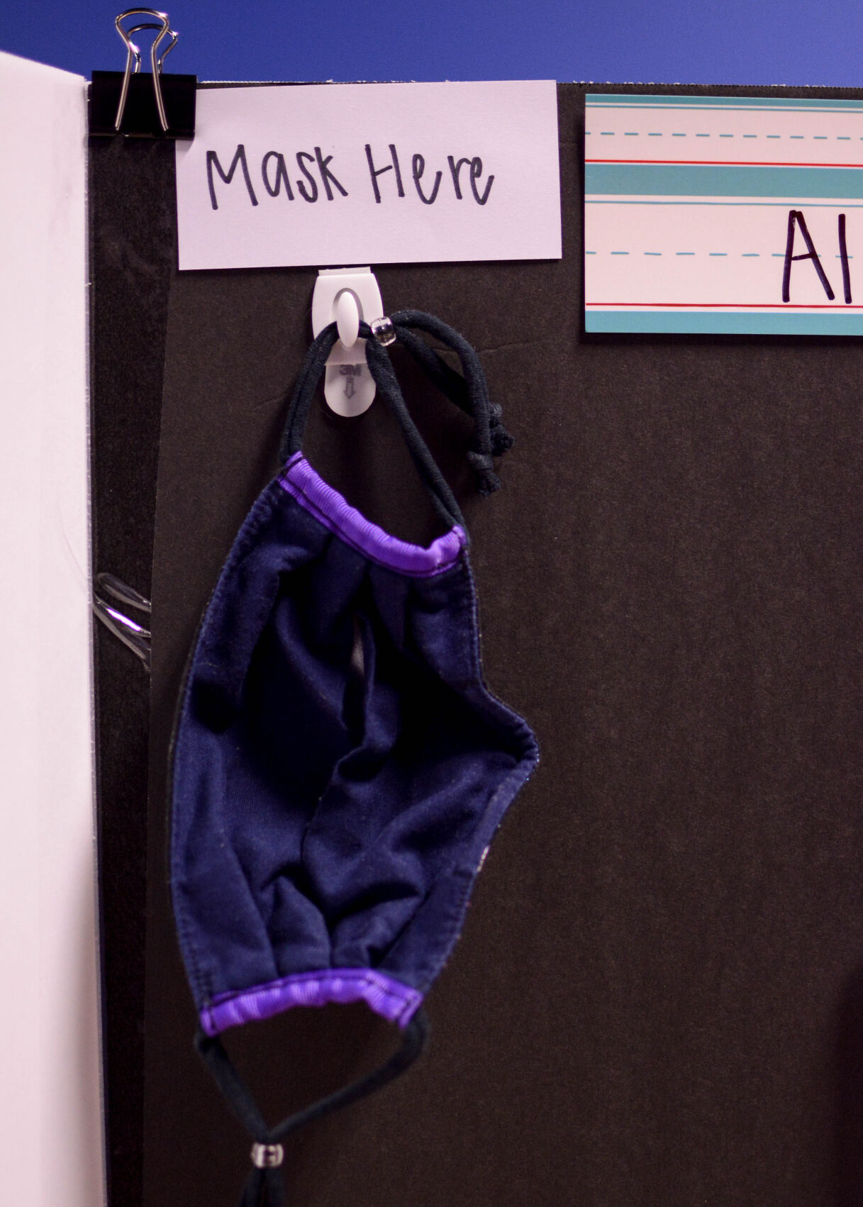 A child's mask hangs from its designated hook